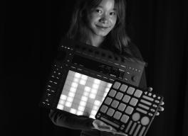 Bethanie Liu holding a series of electronic digital instruments and samplers