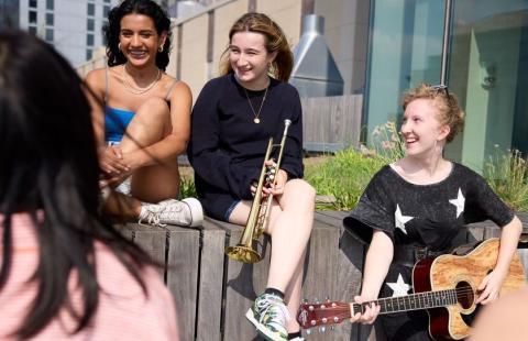 Summer Programs Aspire students sit outside with their instruments